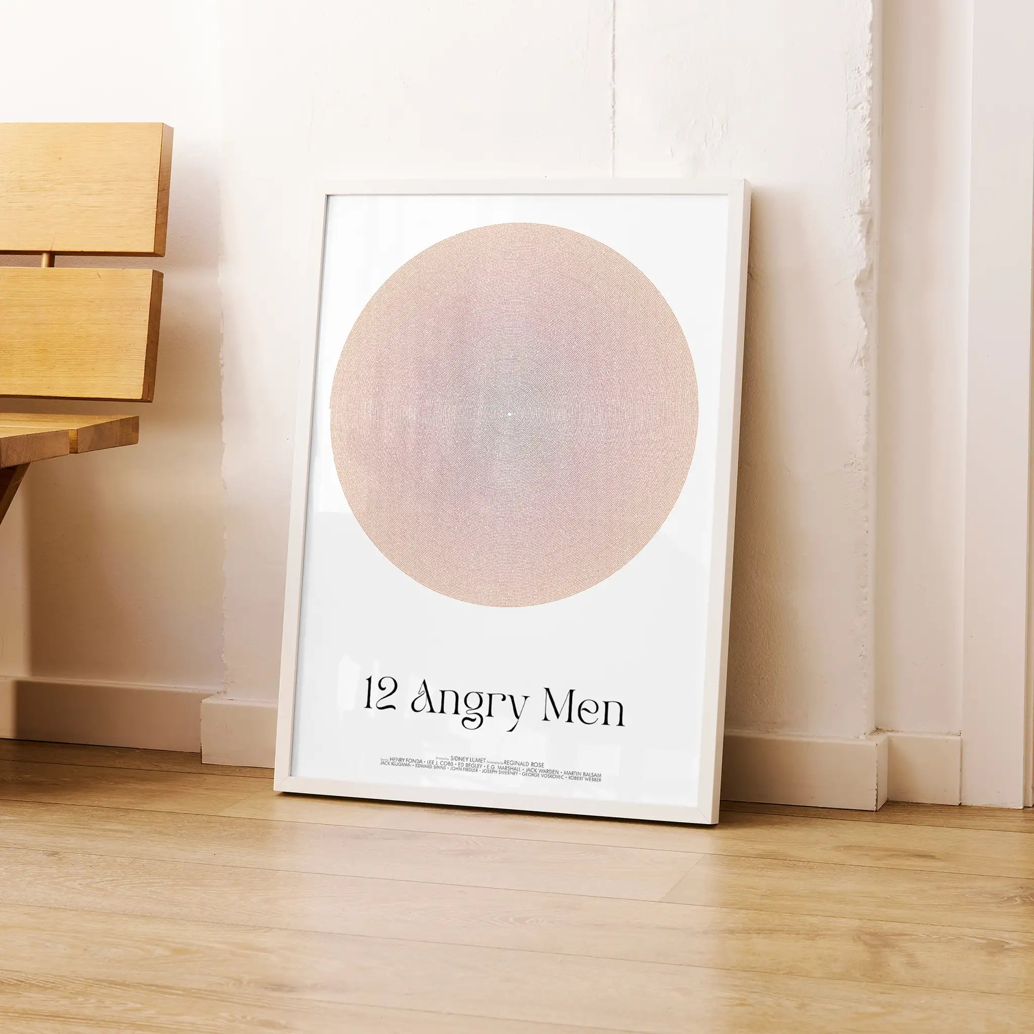 Framed poster titled '12 Angry Men' on a wooden floor against a white wall.