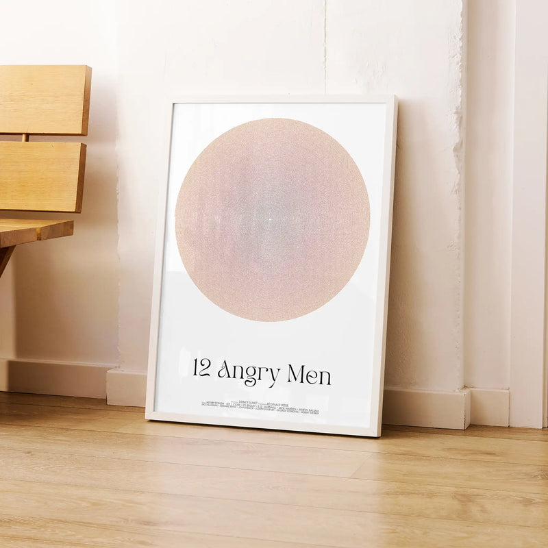 Framed poster titled '12 Angry Men' on a wooden floor against a white wall.