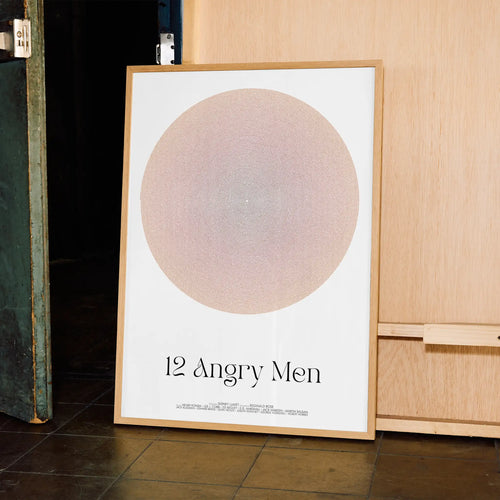 Framed poster titled '12 Angry Men' leaning against a wooden cabinet.