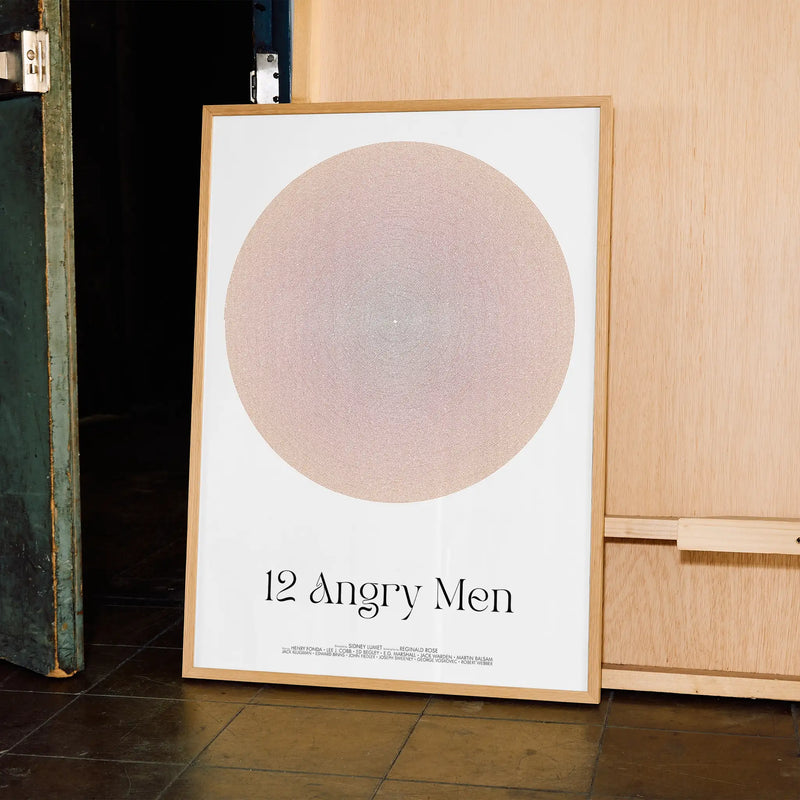 Framed poster titled '12 Angry Men' leaning against a wooden cabinet.