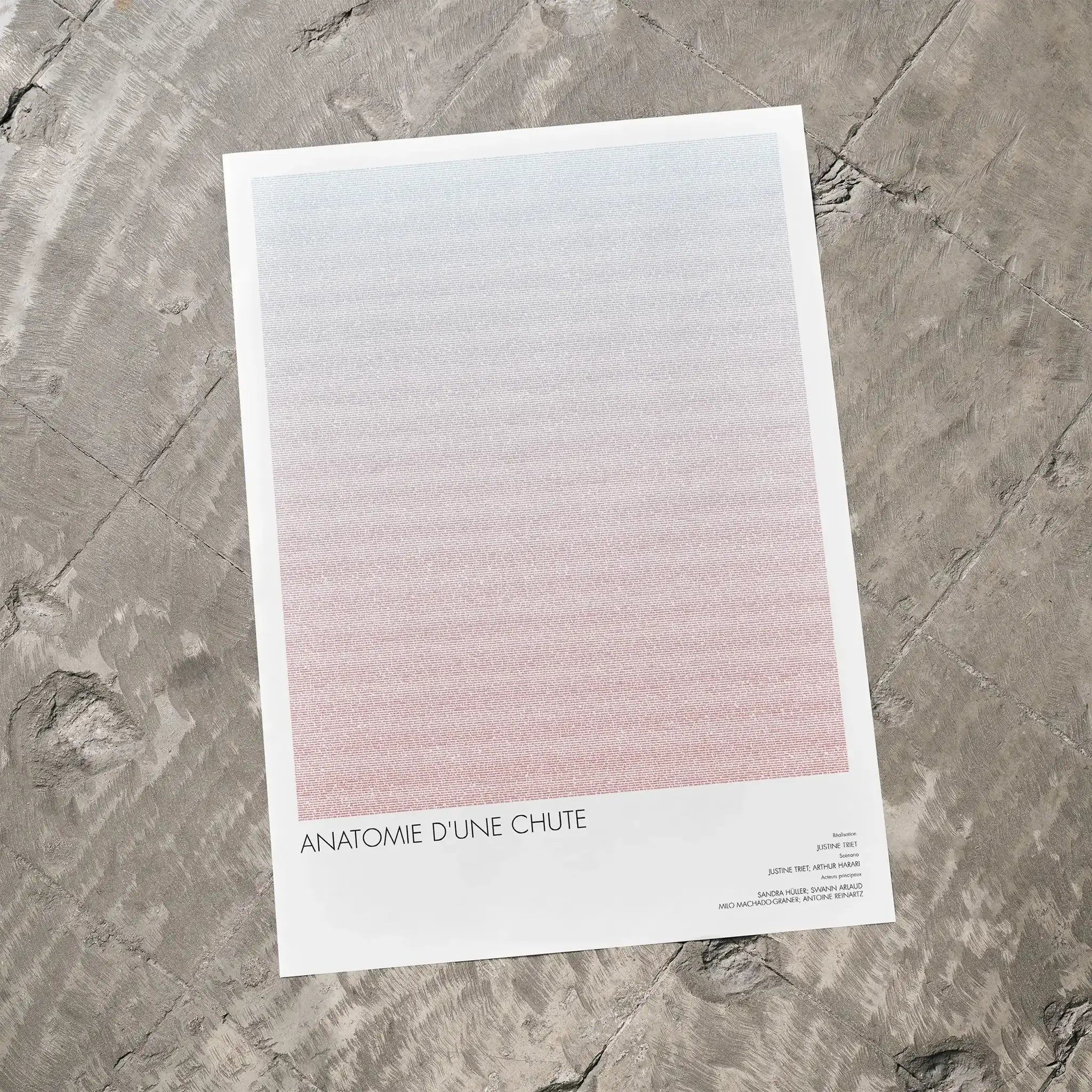 A Anatomie d'une chute movie script poster laid flat on a textured floor surface.