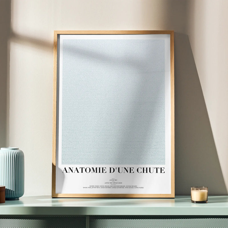 A framed Anatomie d'une chute movie script poster displayed in a simple modern interior.