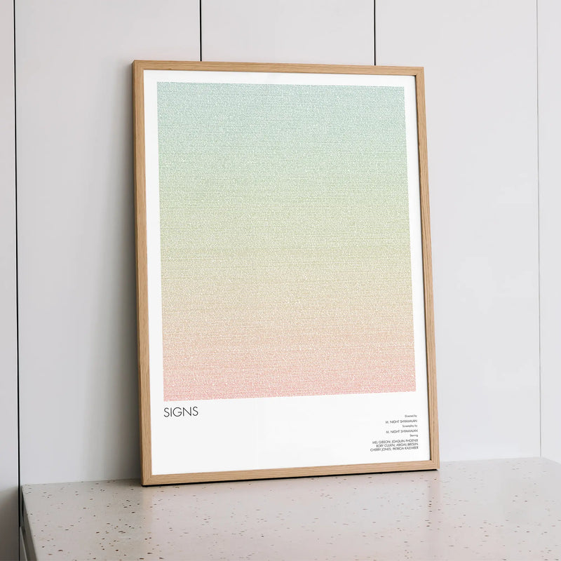 A framed Signs movie script poster styled within a calm interior space.