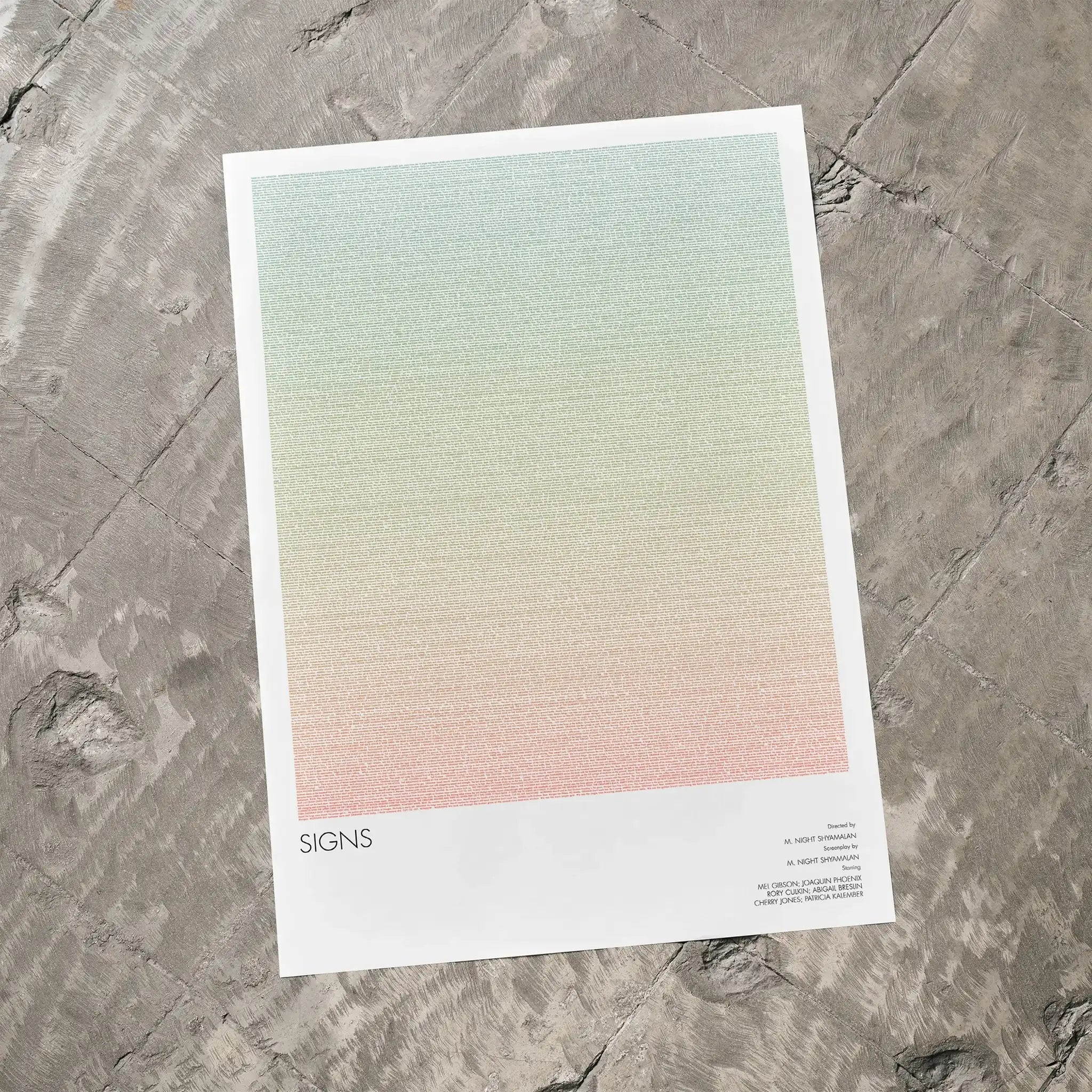 A Signs movie script poster laid flat on a textured floor surface.