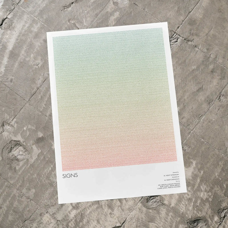 A Signs movie script poster laid flat on a textured floor surface.