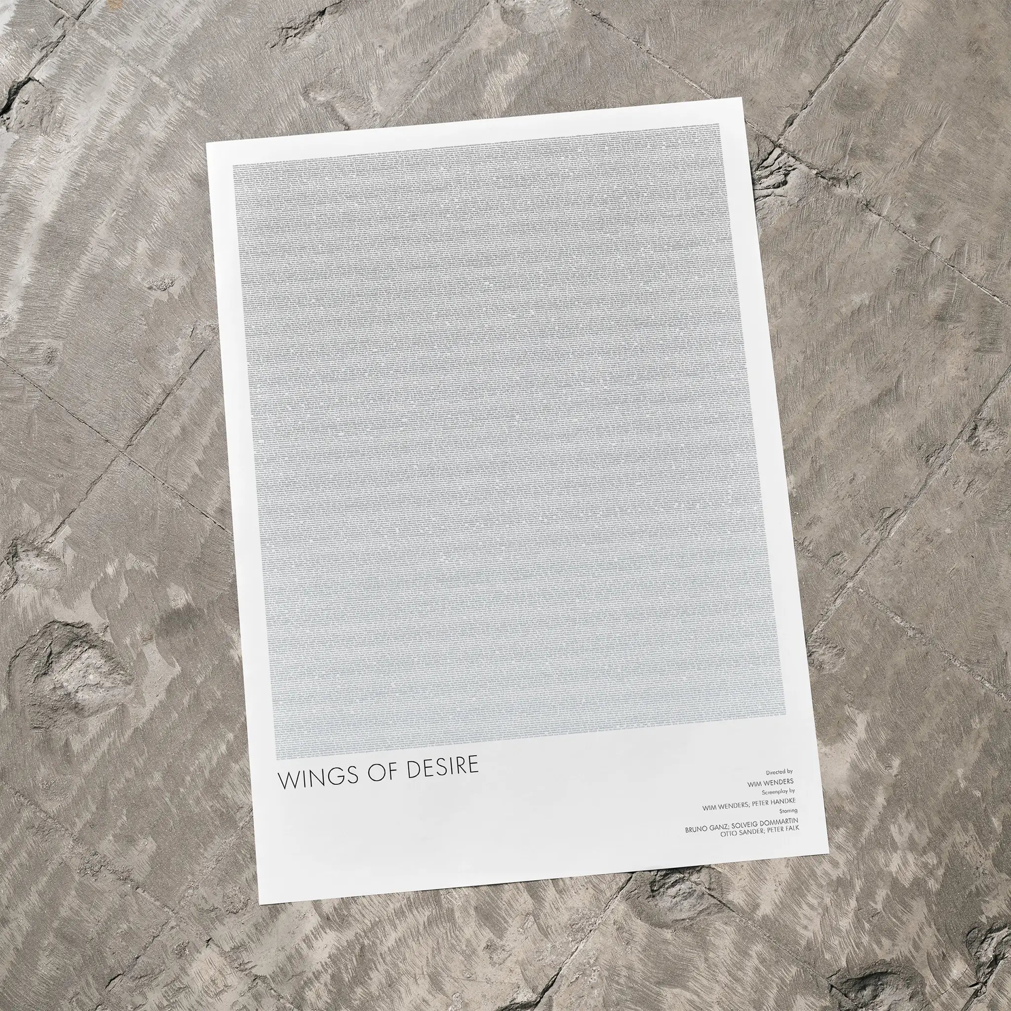 A Wings of Desire movie script poster laid flat on a textured floor surface.