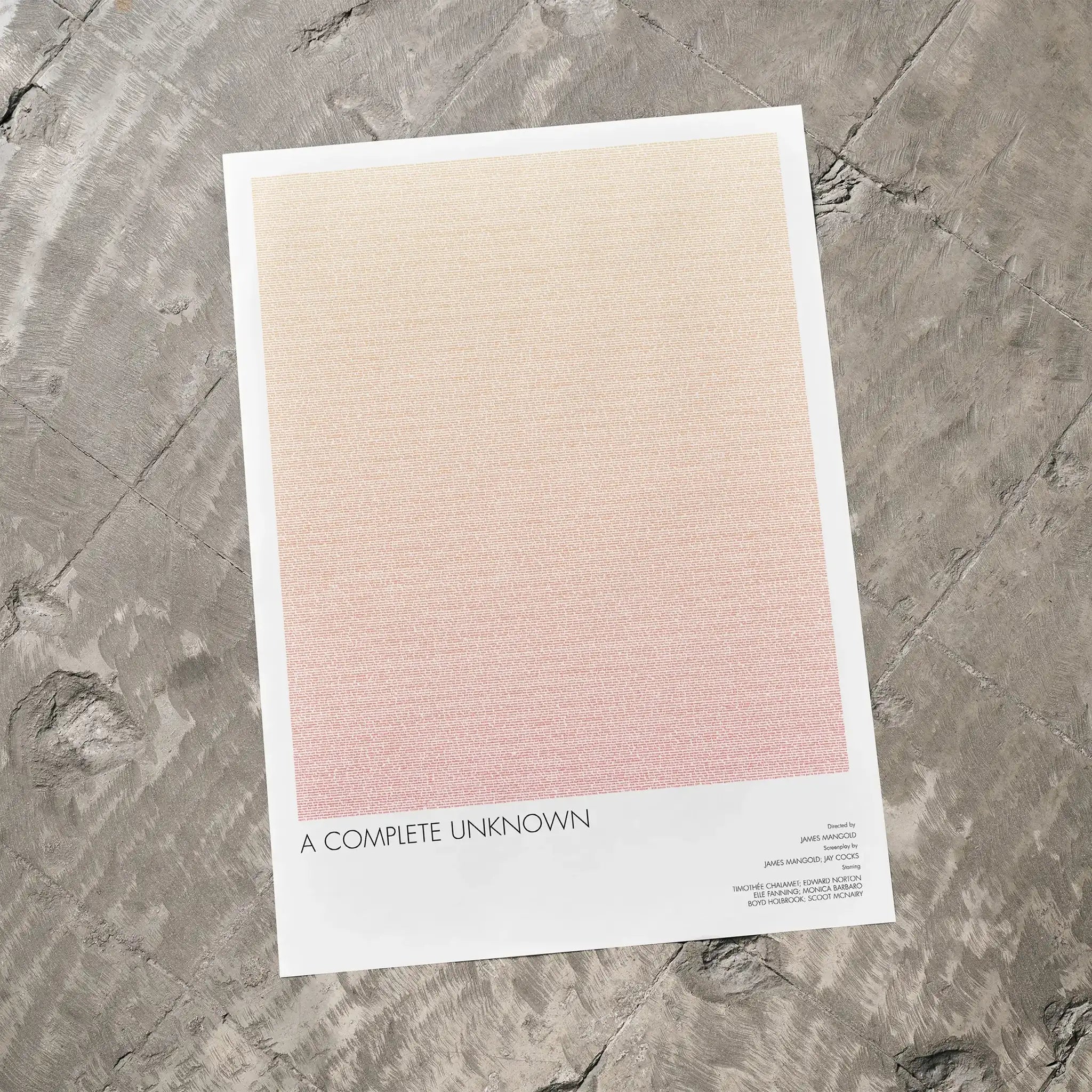 A A Complete Unknown movie script poster laid flat on a textured floor surface.