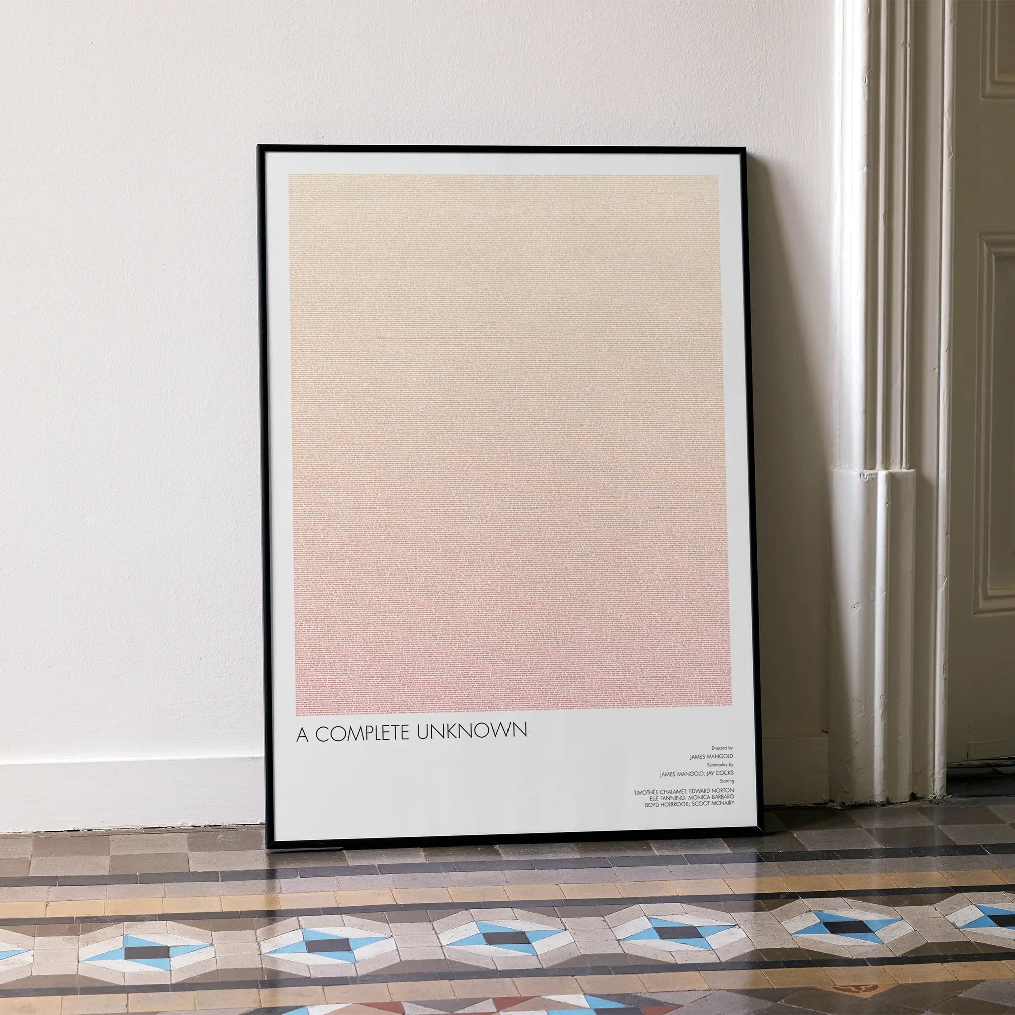 A framed A Complete Unknown movie script poster leaning against a wall in a minimalist interior.