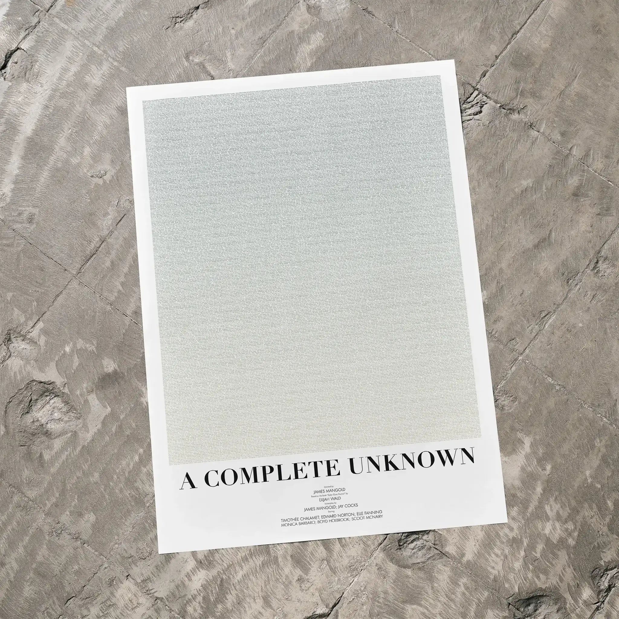 A A Complete Unknown movie script poster laid flat on a textured floor surface.