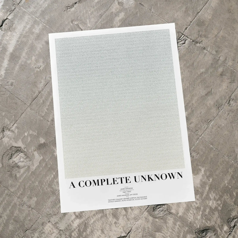 A A Complete Unknown movie script poster laid flat on a textured floor surface.