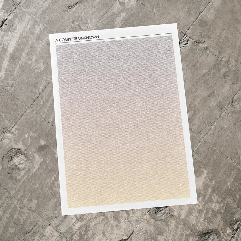 A A Complete Unknown movie script poster laid flat on a textured floor surface.