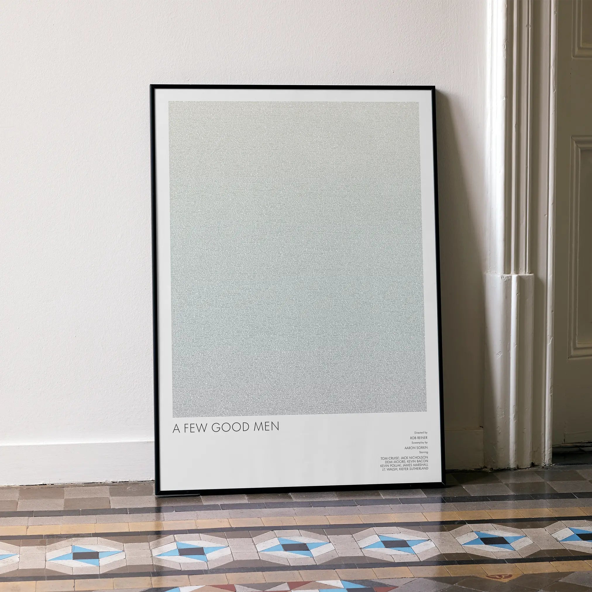 A framed A Few Good Men movie script poster leaning against a wall in a minimalist interior.