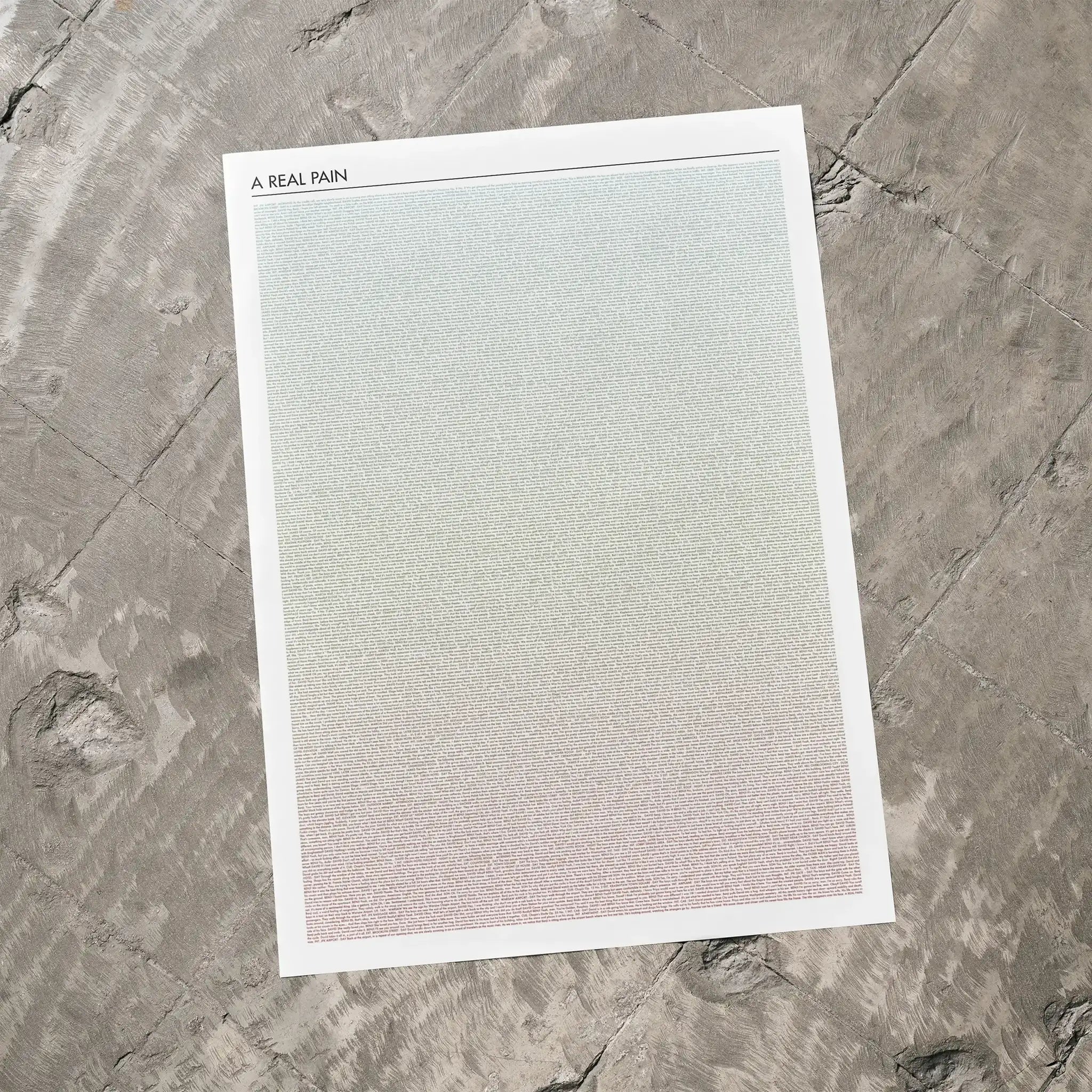 A A Real Pain movie script poster laid flat on a textured floor surface.