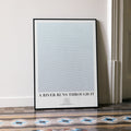 A framed A River Runs Through It movie script poster leaning against a wall in a minimalist interior.