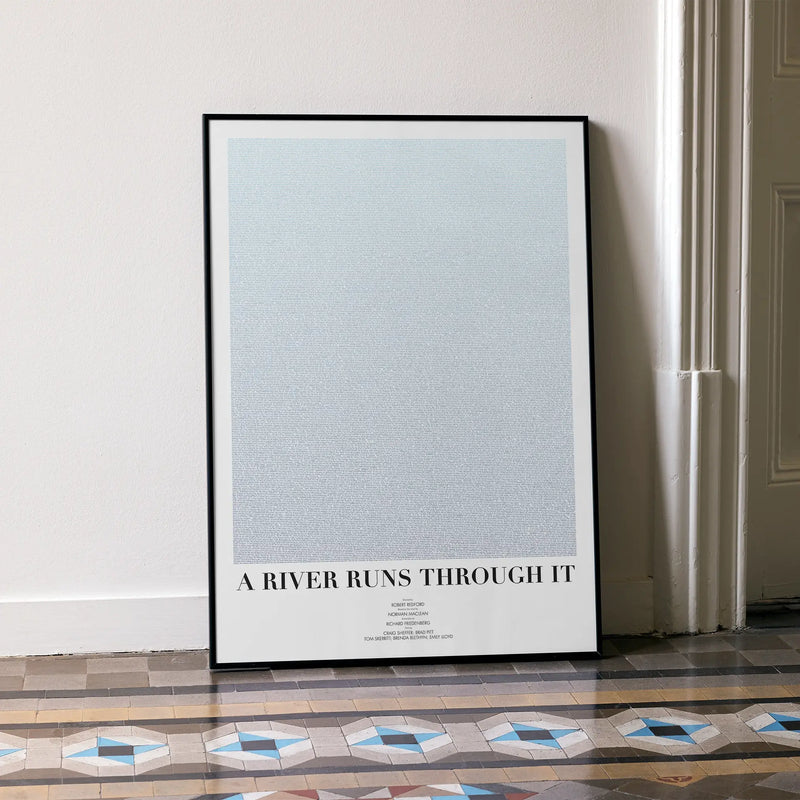 A framed A River Runs Through It movie script poster leaning against a wall in a minimalist interior.