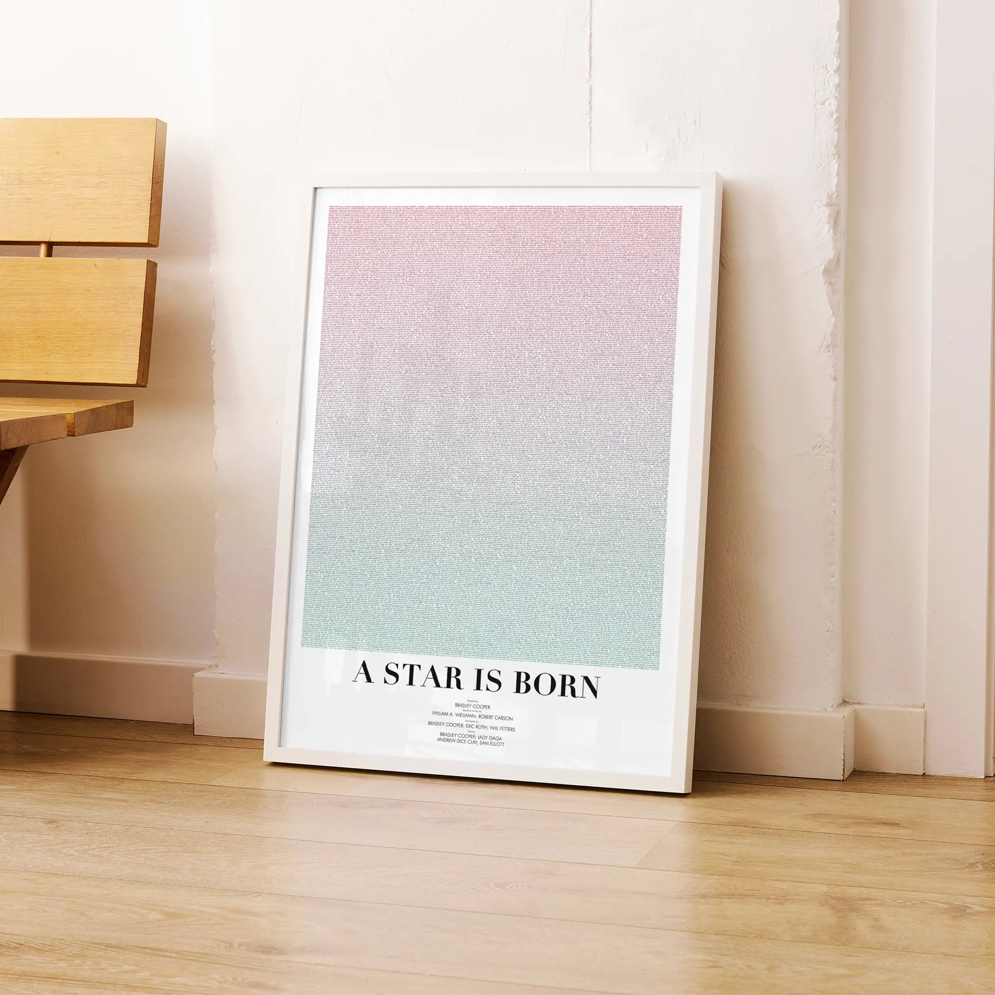 A framed A Star is Born movie script poster leaning against a wall in a modern interior.