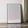 A framed minimalist art print leaning against a white wall on a patterned tiled floor. The print features a large textured square in a soft gray-to-pale pink gradient with the text 'A WOMAN UNDER THE INFLUENCE' at the bottom.