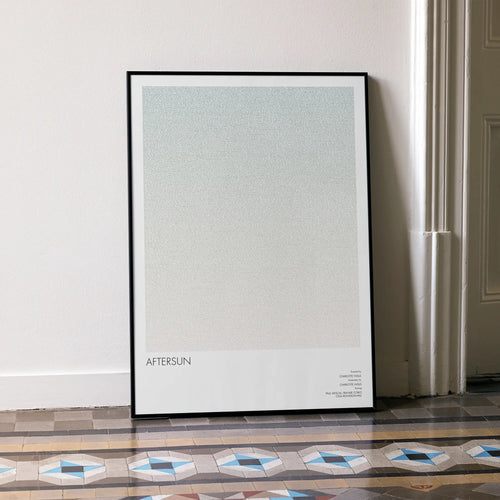 A framed Aftersun movie script poster leaning against a wall in a minimalist interior.
