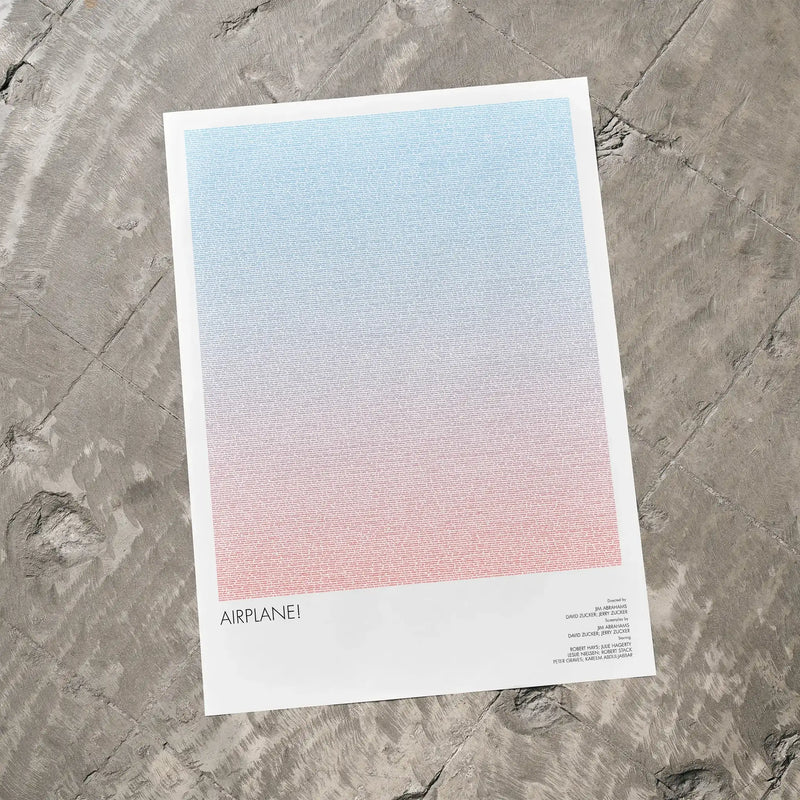 A Airplane movie script poster laid flat on a textured floor surface.