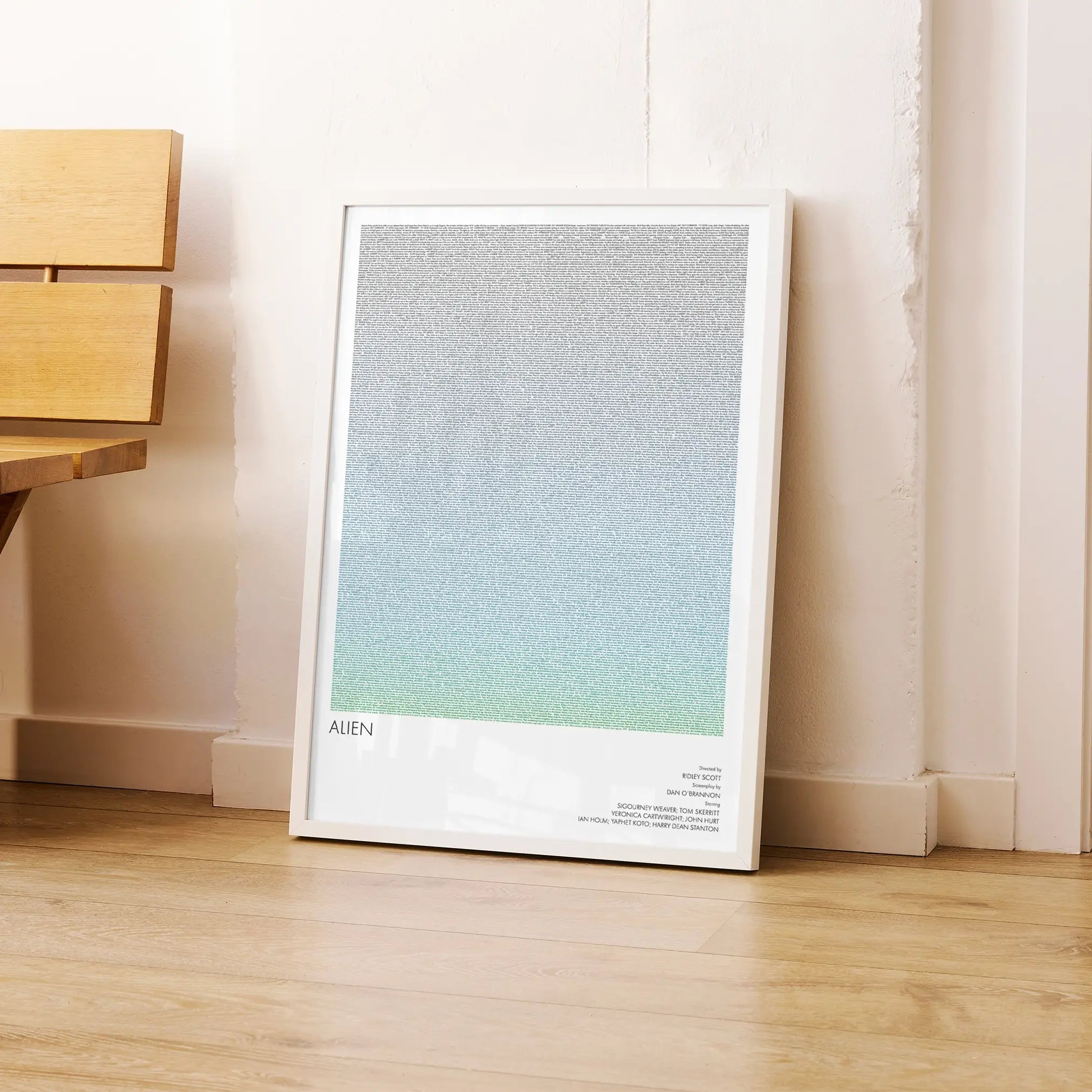 A framed Alien movie script poster leaning against a wall in a modern interior.