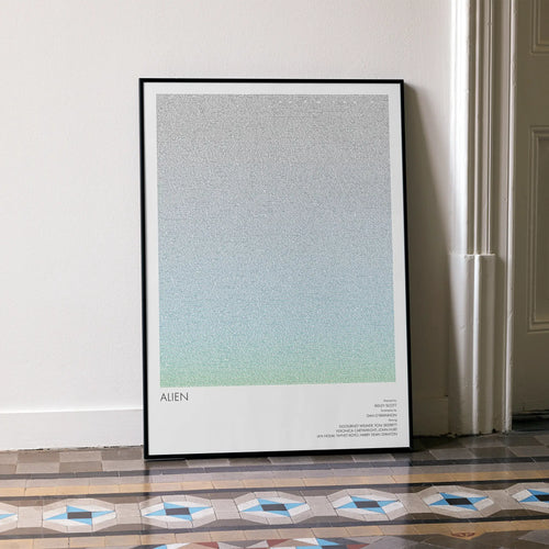 A framed Alien movie script poster leaning against a wall in a minimalist interior.