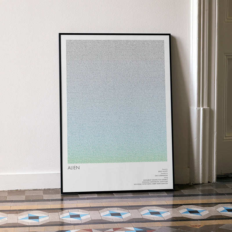 A framed Alien movie script poster leaning against a wall in a minimalist interior.
