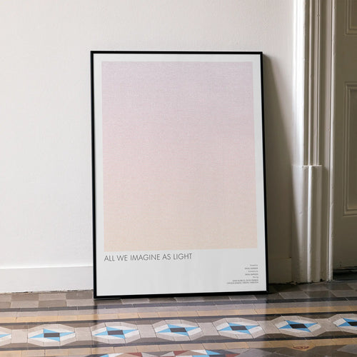 A framed All We Imagine as Light movie script poster leaning against a wall in a minimalist interior.
