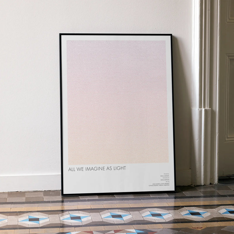 A framed All We Imagine as Light movie script poster leaning against a wall in a minimalist interior.