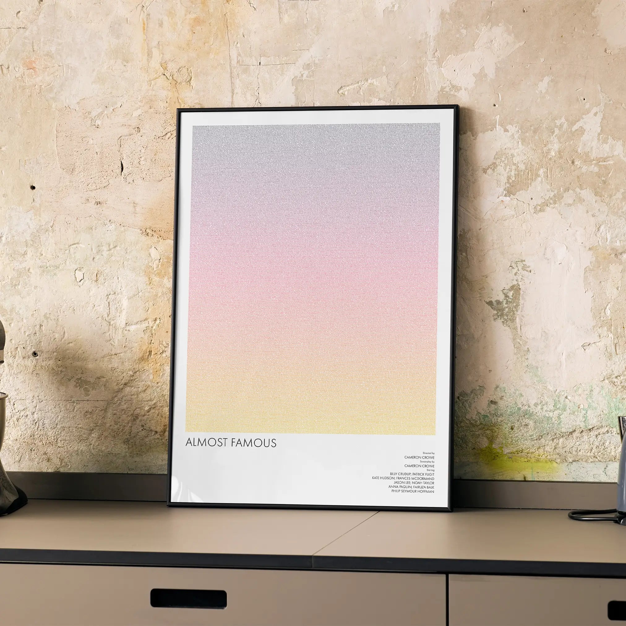 A framed Almost Famous movie script poster displayed on a cabinet in a minimalist interior.