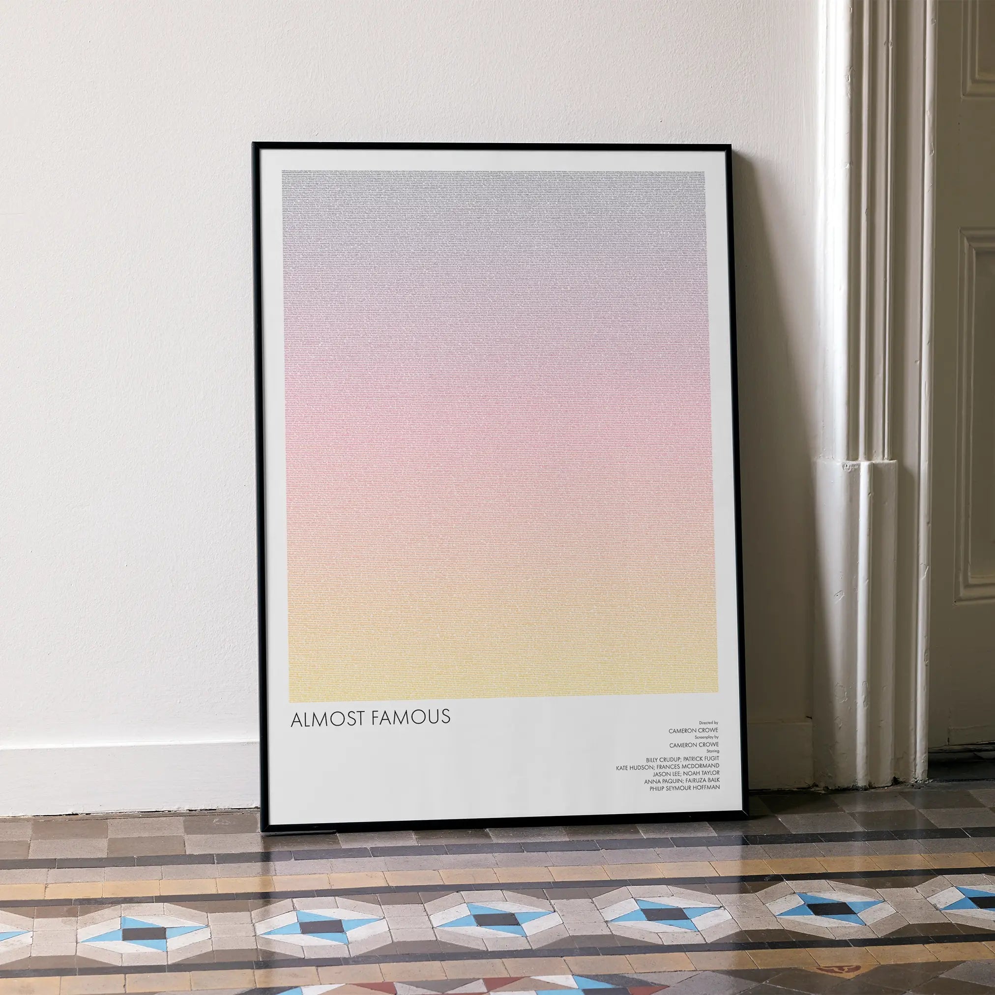 A framed Almost Famous movie script poster leaning against a wall in a minimalist interior.