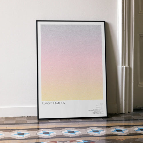A framed Almost Famous movie script poster leaning against a wall in a minimalist interior.
