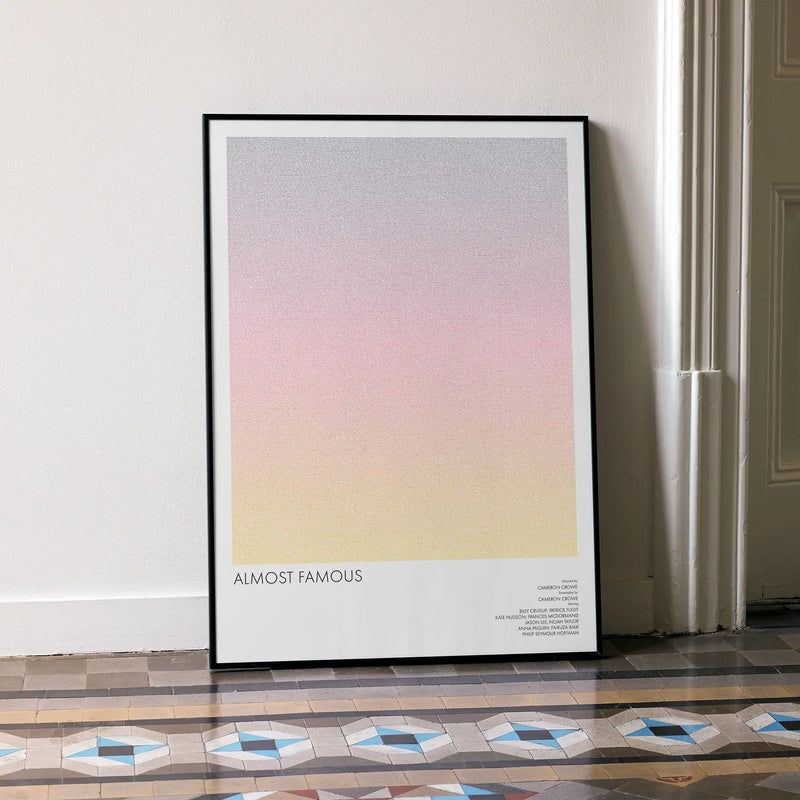 A framed Almost Famous movie script poster leaning against a wall in a minimalist interior.