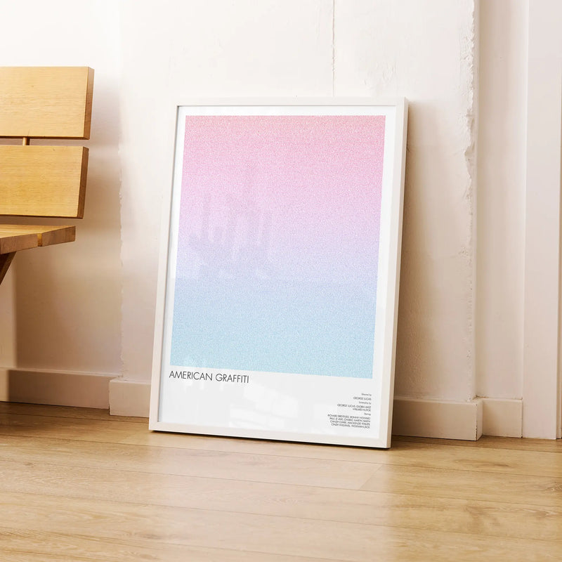 A framed American Graffiti movie script poster leaning against a wall in a modern interior.