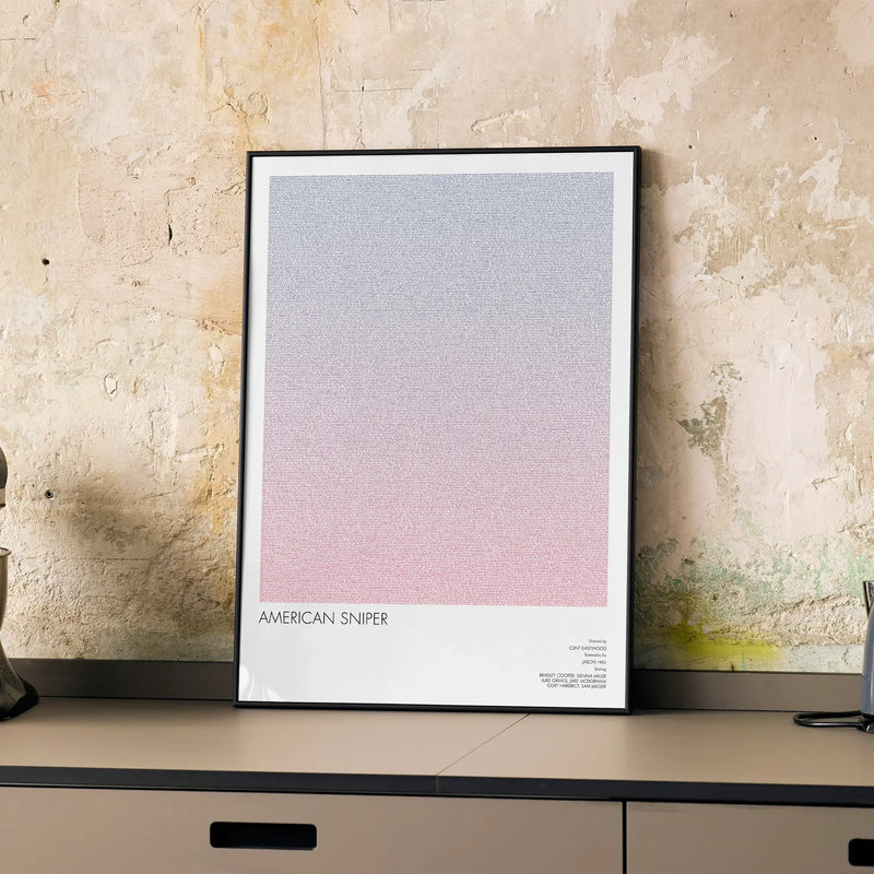 A framed American Sniper movie script poster displayed on a cabinet in a minimalist interior.