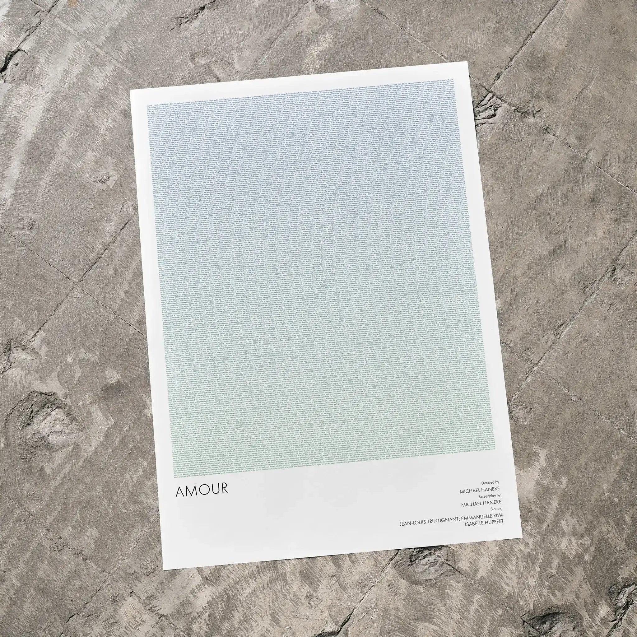 A Amour movie script poster laid flat on a textured floor surface.