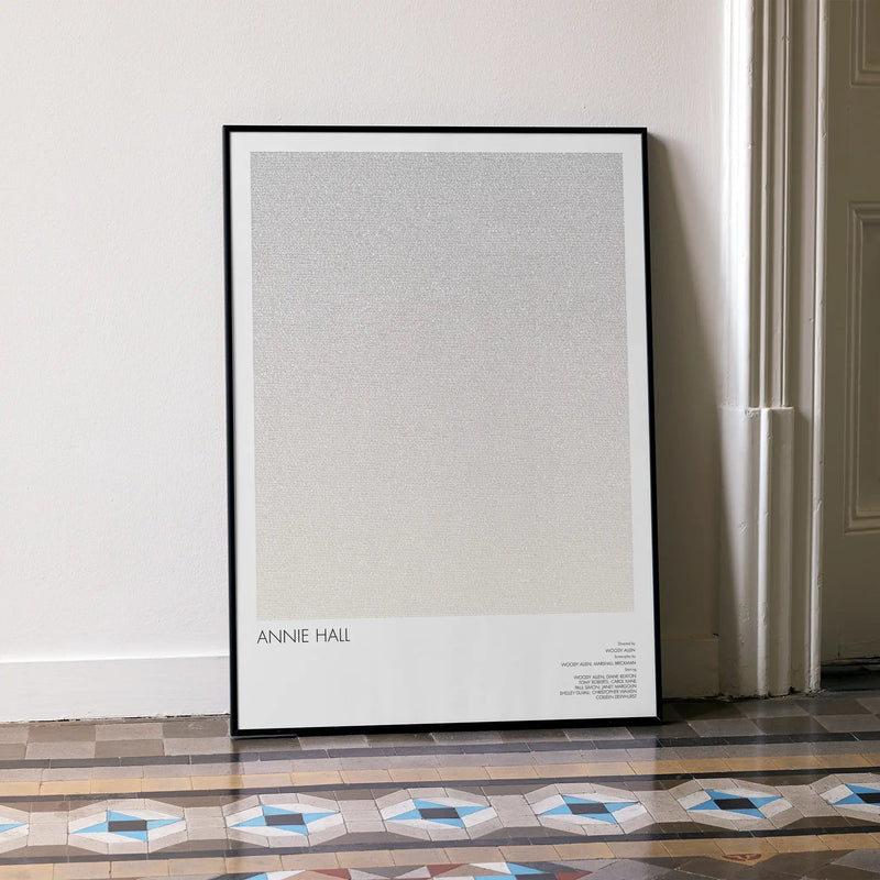 A framed Annie Hall movie script poster leaning against a wall in a minimalist interior.