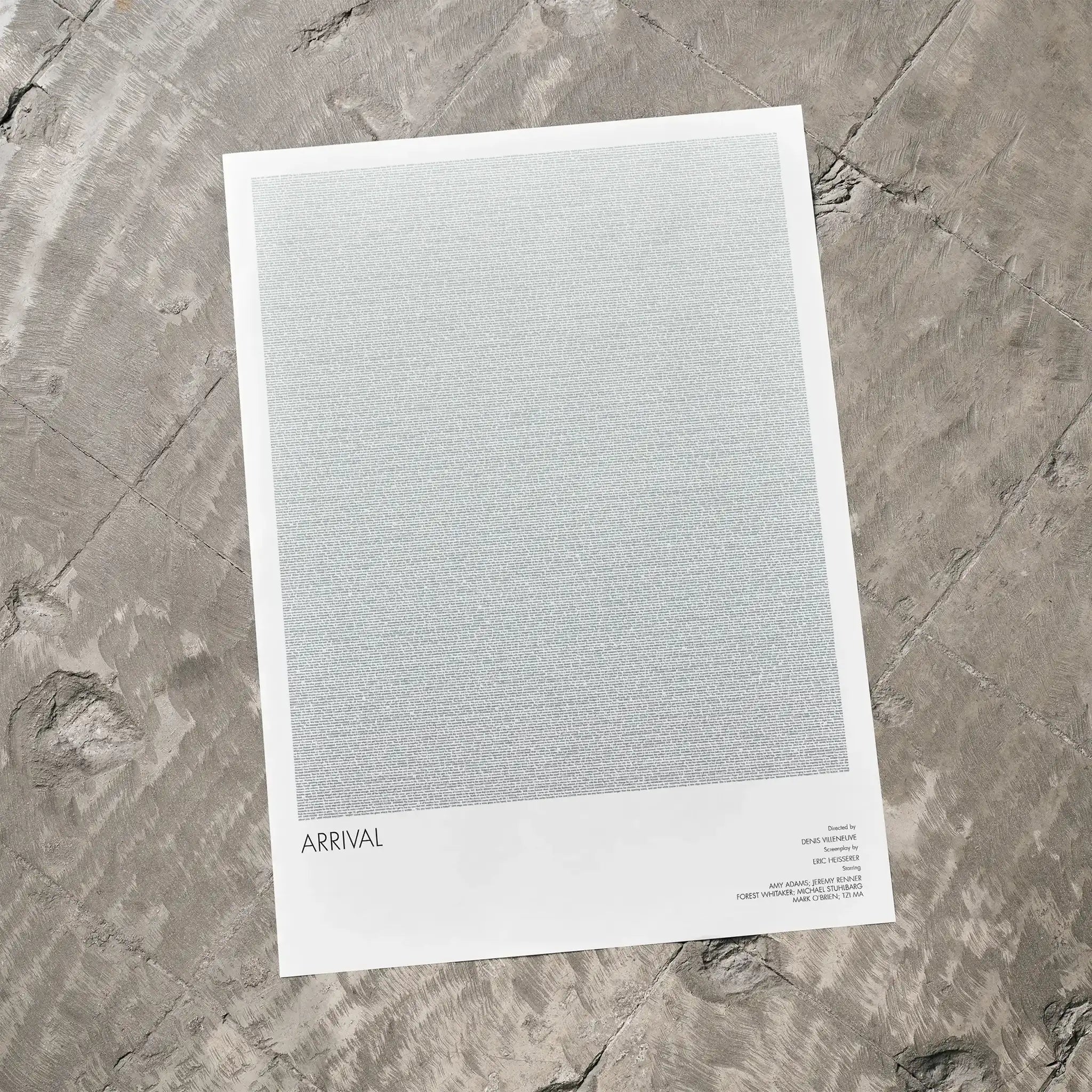 A Arrival movie script poster laid flat on a textured floor surface.