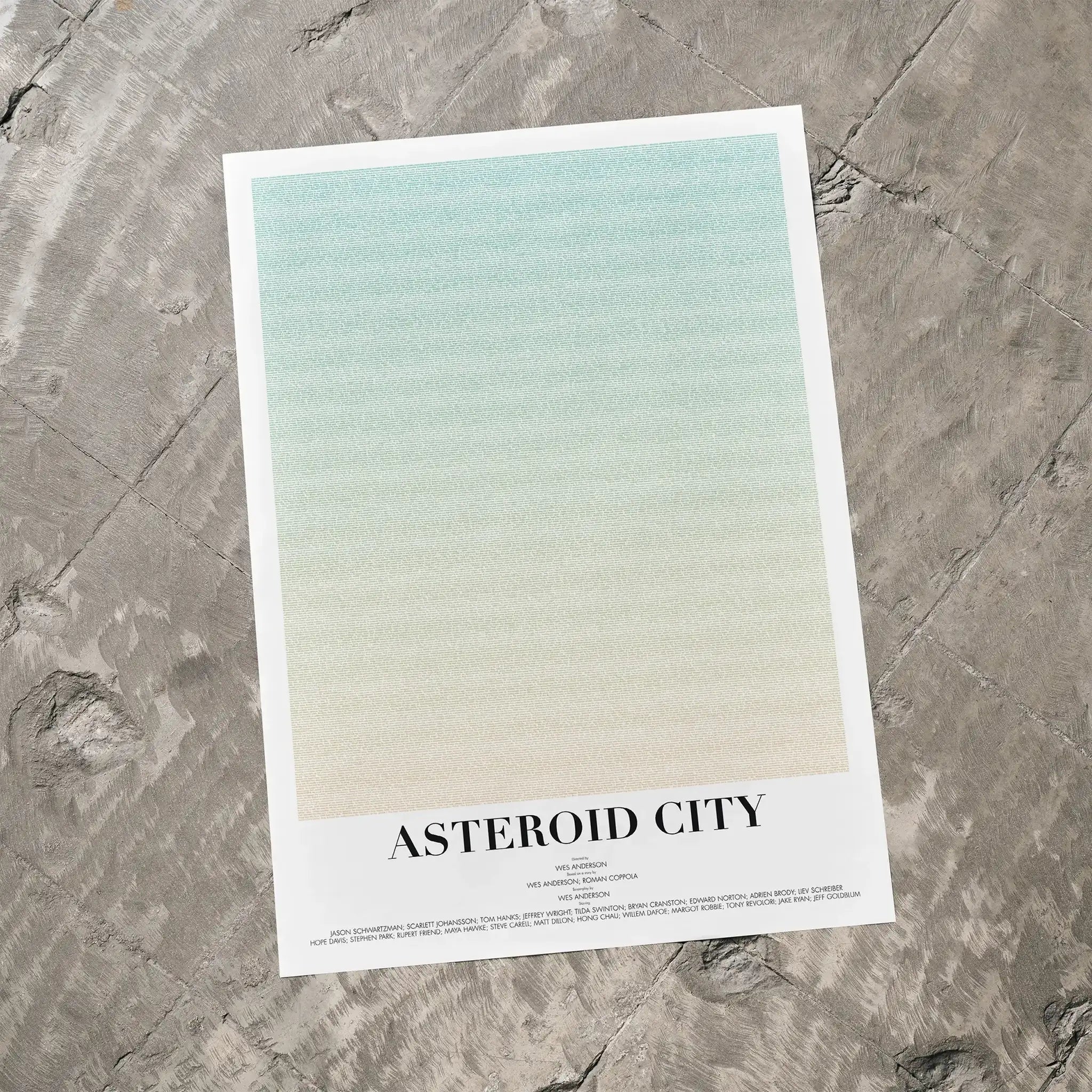 A Asteroid City movie script poster laid flat on a textured floor surface.