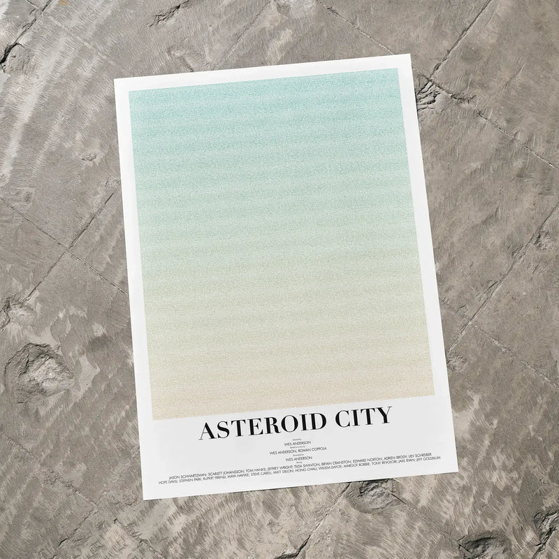 A Asteroid City movie script poster laid flat on a textured floor surface.