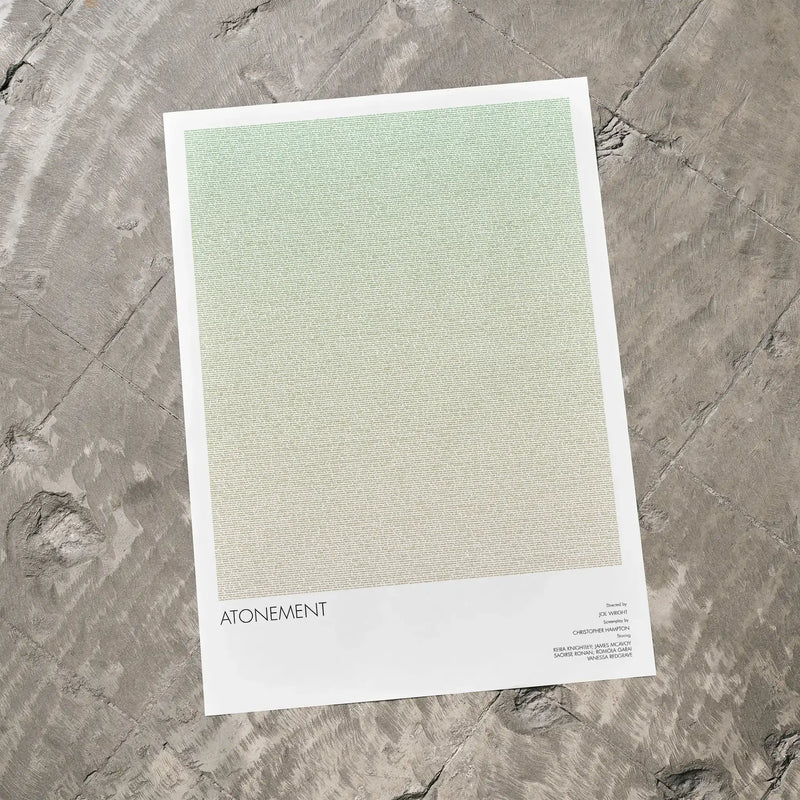 A Atonement movie script poster laid flat on a textured floor surface.