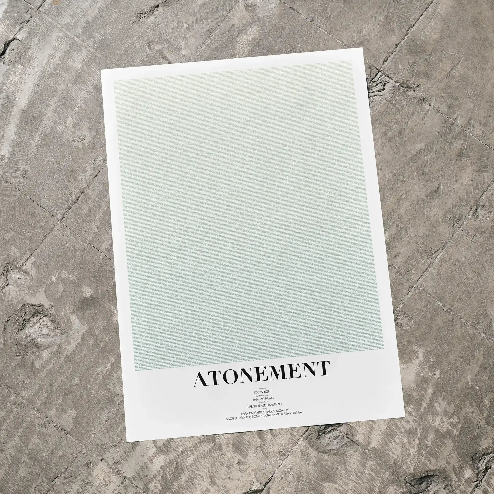 A Atonement movie script poster laid flat on a textured floor surface.