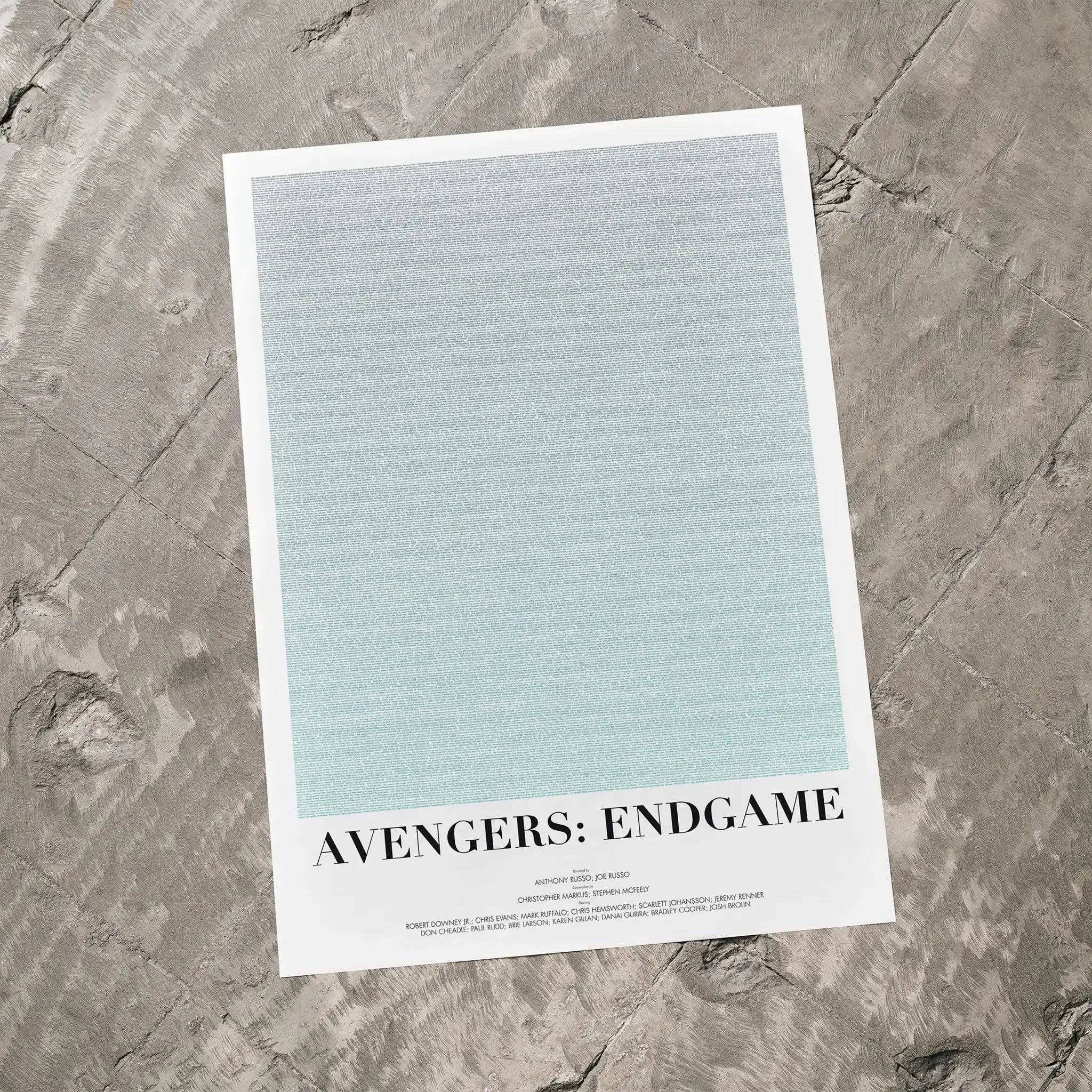A Avengers: Endgame movie script poster laid flat on a textured floor surface.