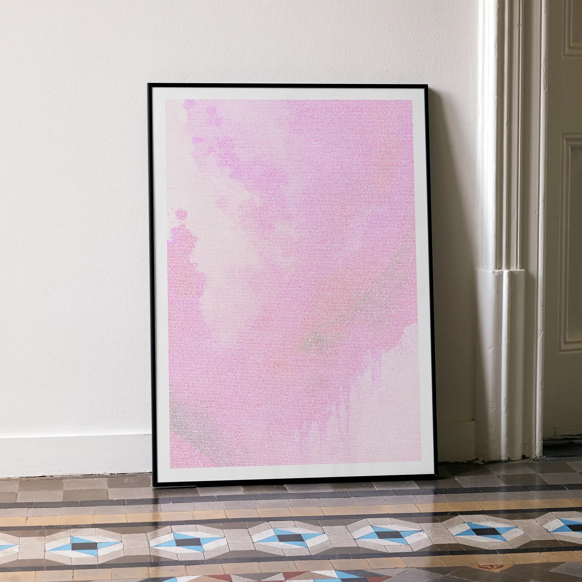 A framed Barbie movie script poster leaning against a wall in a minimalist interior.