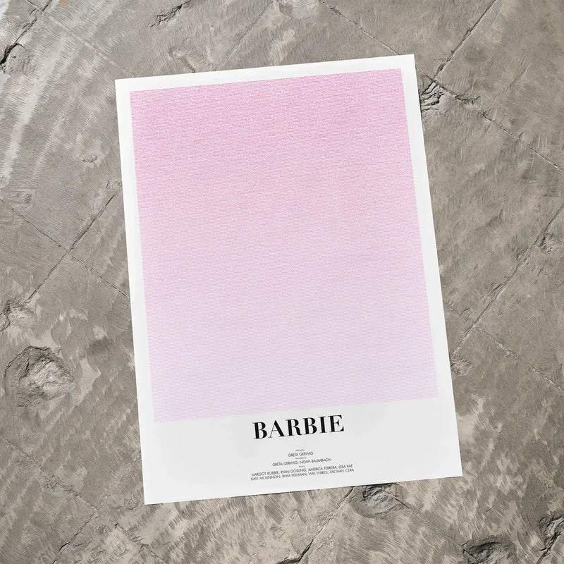 A Barbie movie script poster laid flat on a textured floor surface.