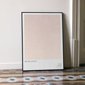 A framed Before Sunset movie script poster leaning against a wall in a minimalist interior.