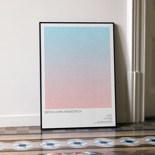 A framed Being John Malkovich movie script poster leaning against a wall in a minimalist interior.