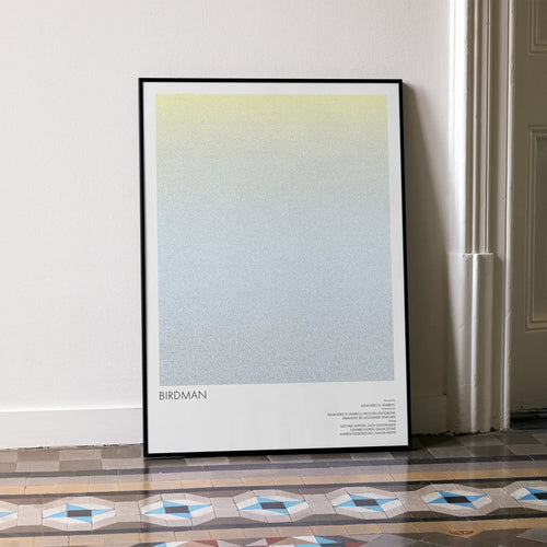 A framed Birdman or movie script poster leaning against a wall in a minimalist interior.