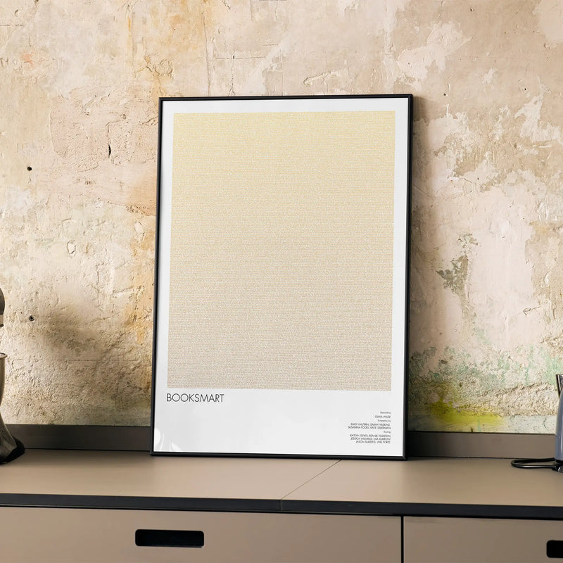A framed Booksmart movie script poster displayed on a cabinet in a minimalist interior.