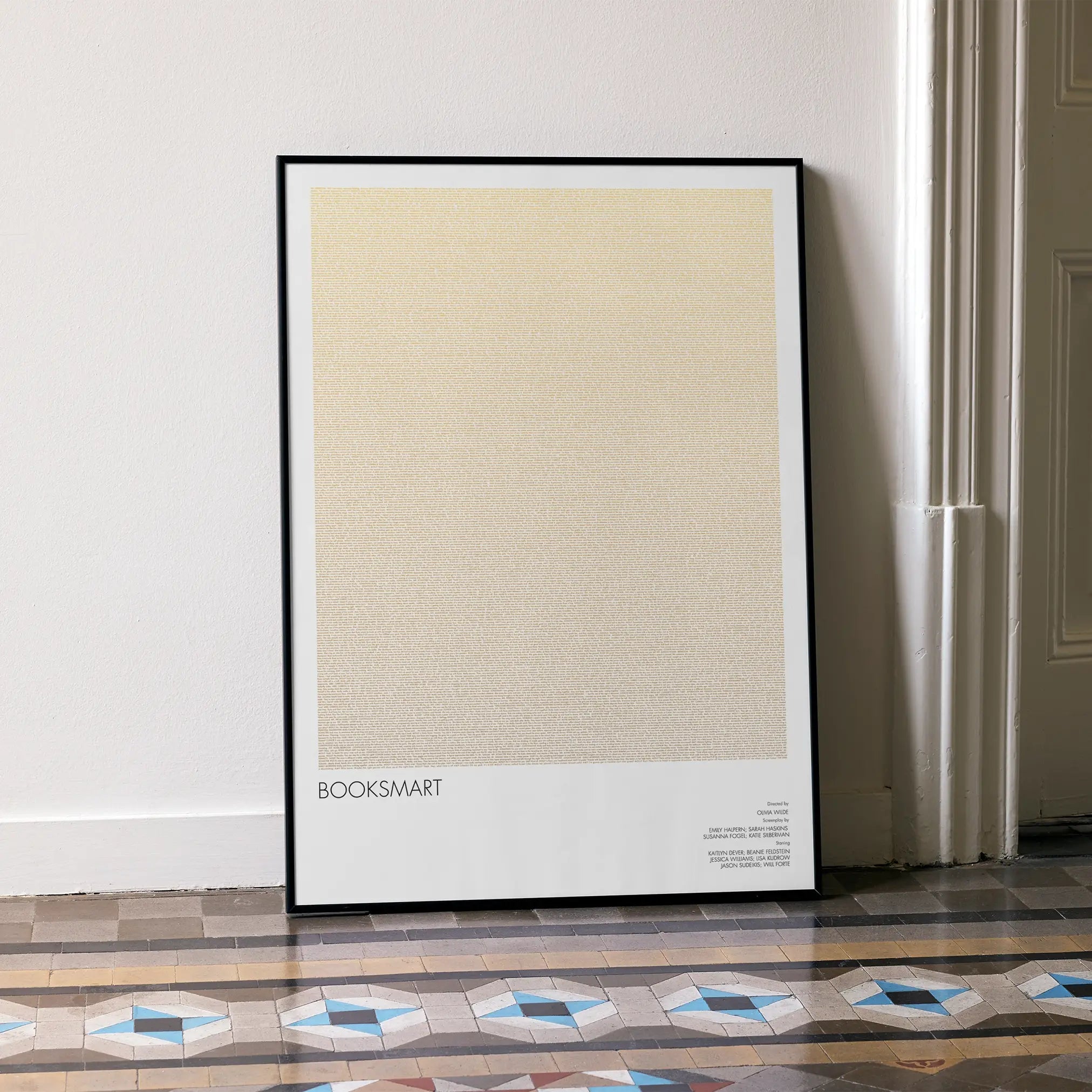 A framed Booksmart movie script poster leaning against a wall in a minimalist interior.