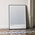 A framed Braveheart movie script poster leaning against a wall in a minimalist interior.